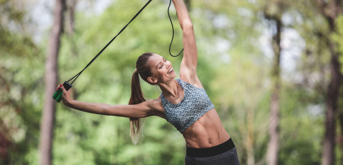 Woman pulling a rope or resistance band doing exercise amongst nature